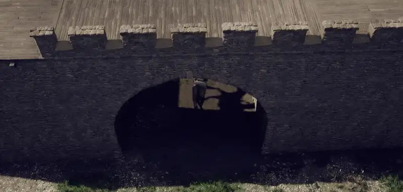 Un mur de fort s'efface pour laisser voir le joueur qui passe derrière
